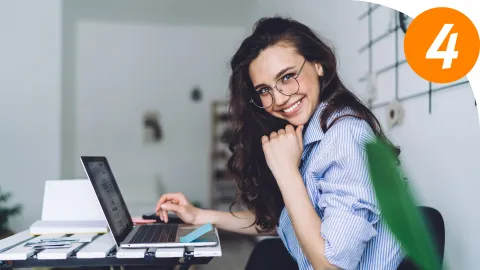 lächelnde Frau sitzt am Laptop | WINGS-Fernstudium