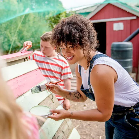 Soziale Arbeit Frau streicht Holz | WINGS-Fernstudium